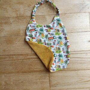 photo du bavoir bébé élastiqué avec motifs caméléons, doublé éponge de coton moutarde