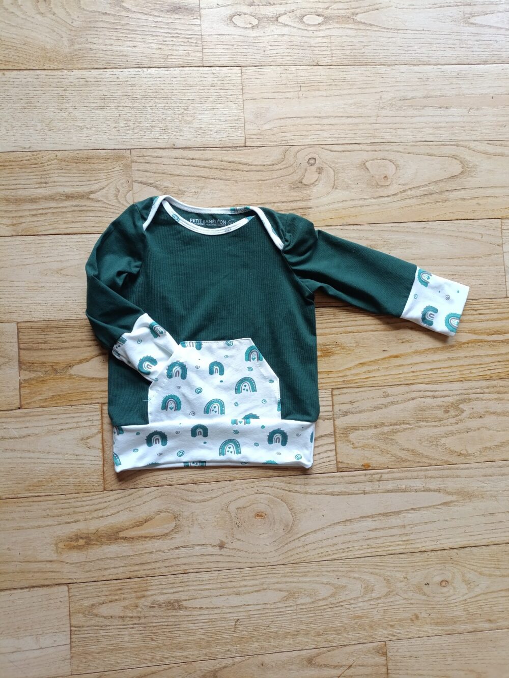 photo du sweat évolutif bébé vert sapin et poche kangourou blanche motif arc en ciel, associée aux poignets et à la bande de bas