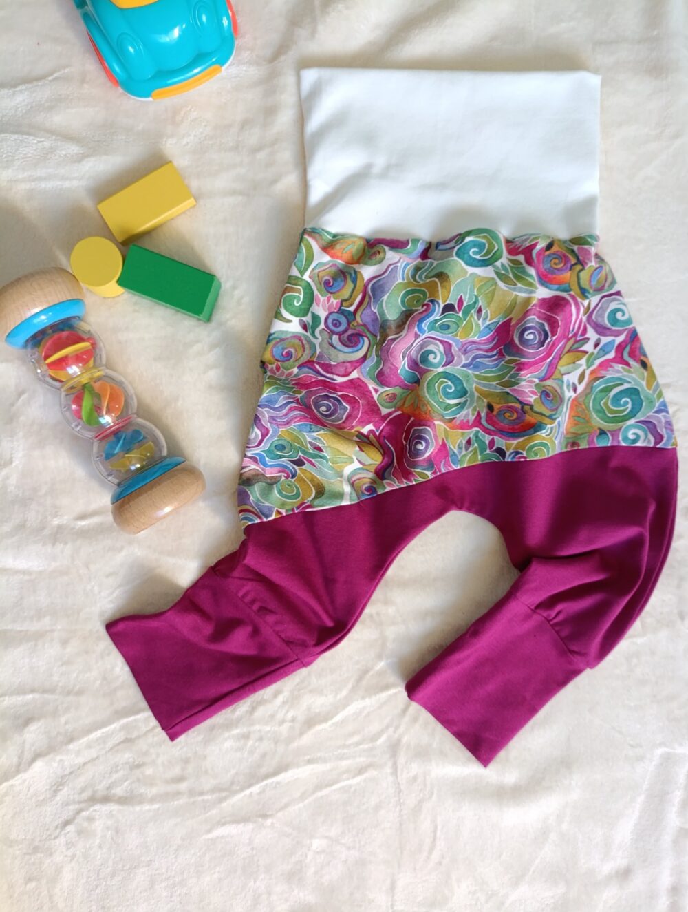 sarouel bébé evolutif à plat sur plaid avec des jouets, ceinture et chevilles dépliés