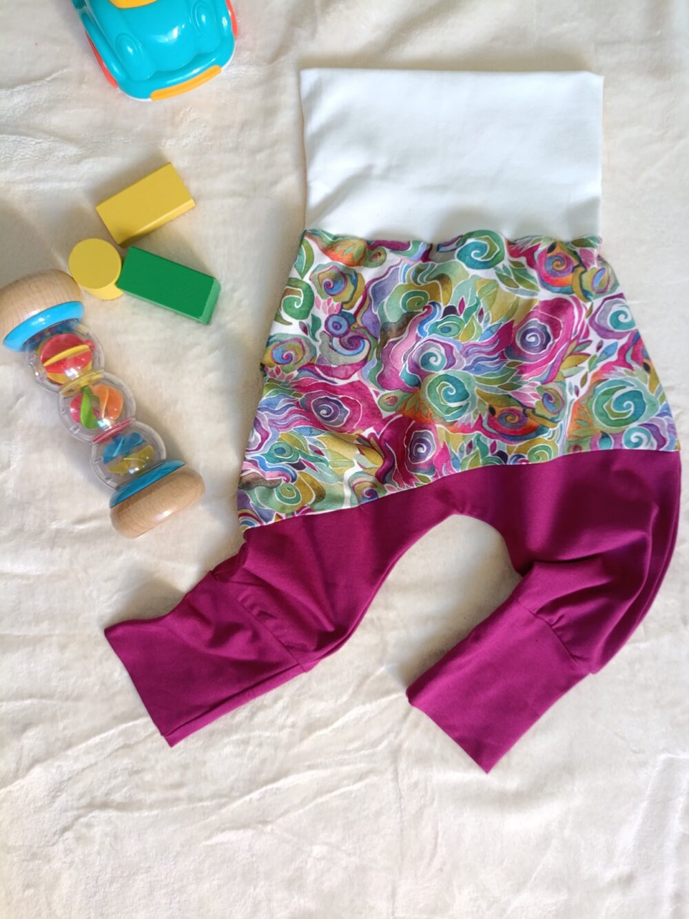 sarouel bébé evolutif à plat sur plaid avec des jouets, ceinture et chevilles dépliés