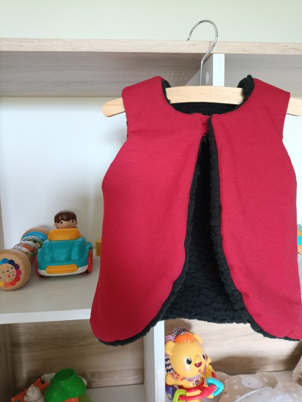 gilet de berger côté bordeaux sur cintre dans une chambre d'enfant