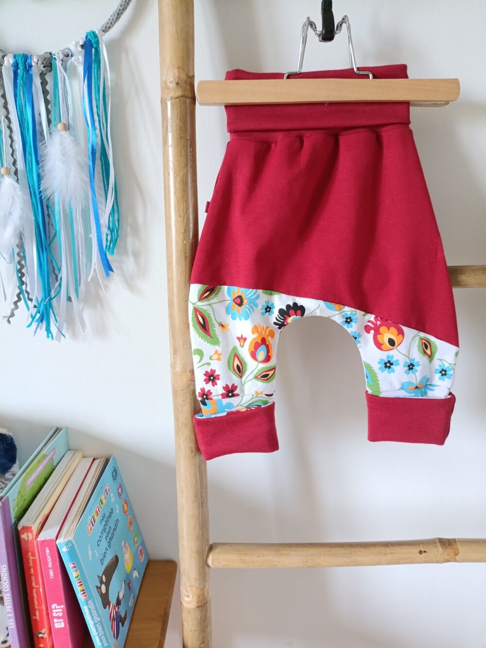 legging bebe évolutif bordeaux fleurs sur cintre dans une chambre d'enfant