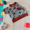 Tee-shirt évolutif pour enfant à manches courtes, en tissu gris chiné à motif de super-héros, avec encolure, poignets et bande de taille orange brique.