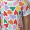 Tee-shirt évolutif pour enfant à manches courtes, en tissu blanc à motif de cœurs multicolores, avec encolure et bandes blanches. Présenté porté.