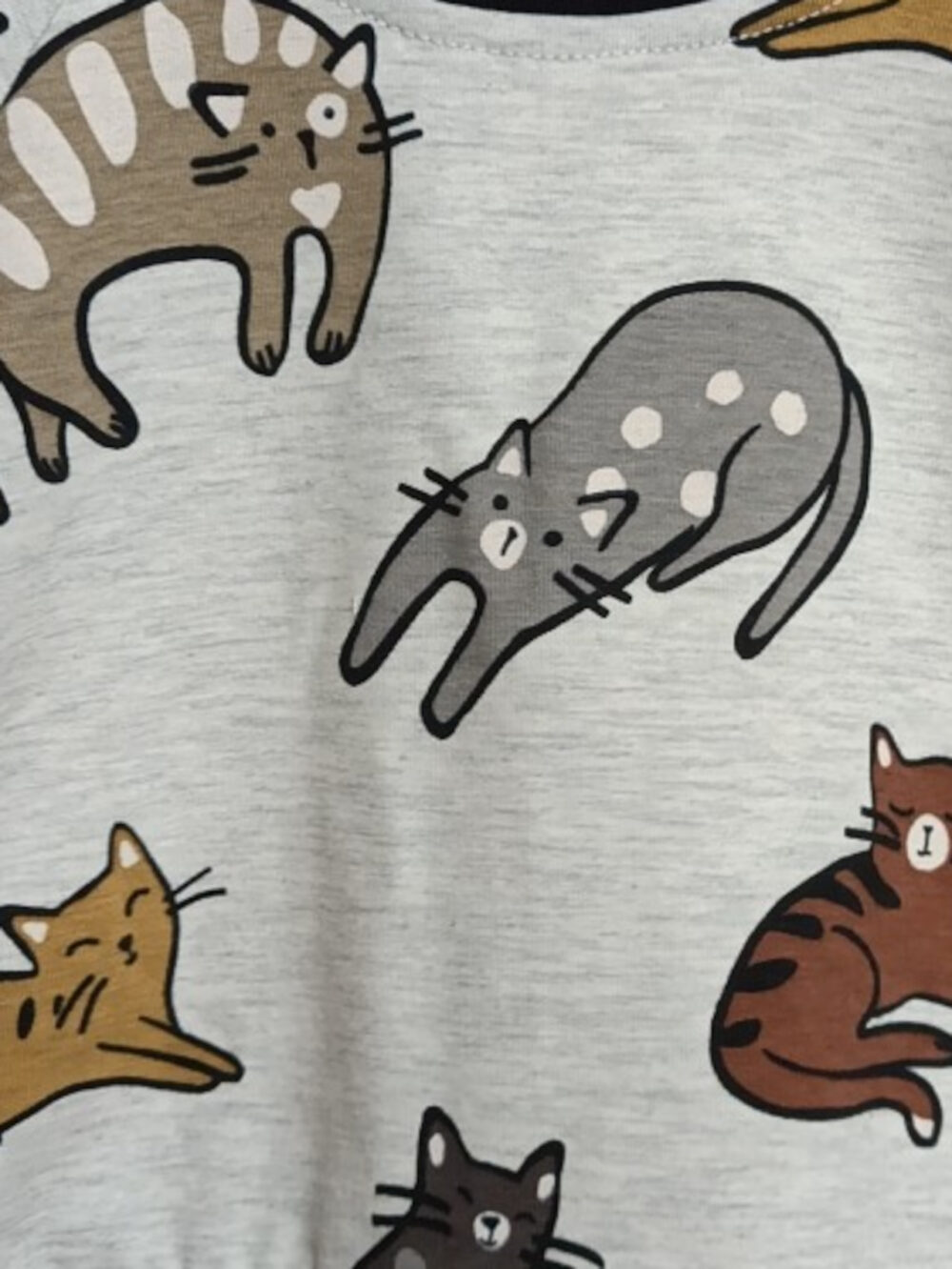 Light gray fabric printed with a repeating pattern of cute, colorful cartoon cats in various poses.